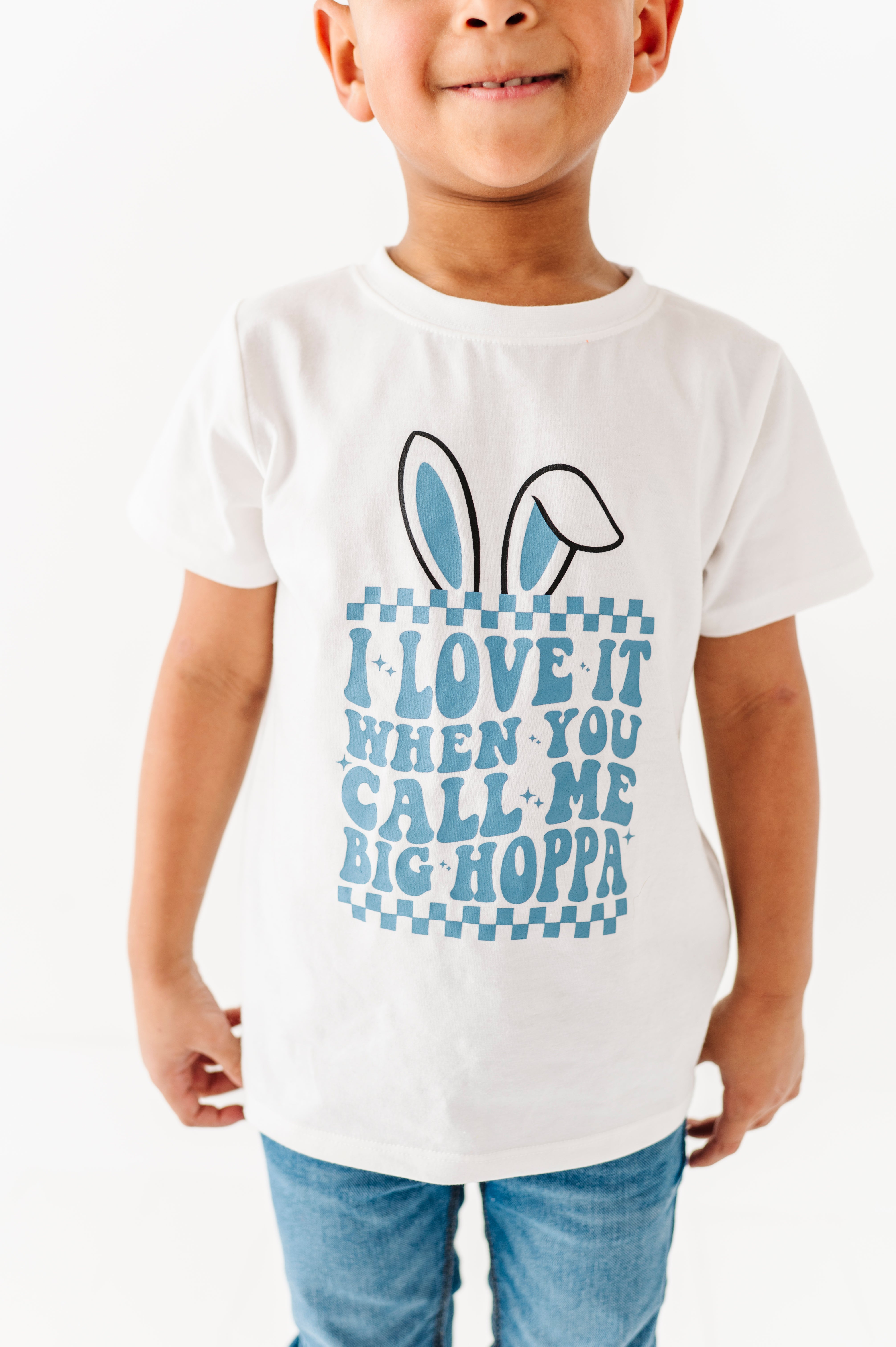 Child wearing a white t-shirt with a blue graphic and text on a white background